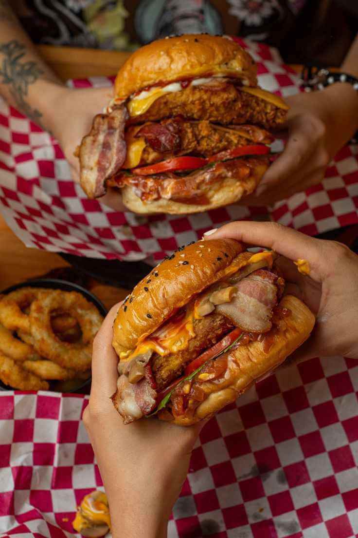 Девушка улыбается и держит бургер Qazmaq на красном фоне