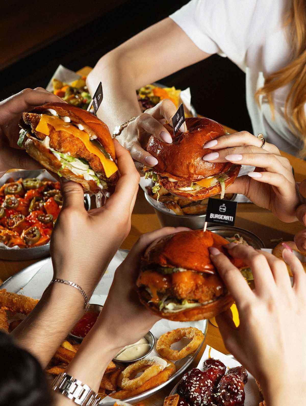 Куриный бургер Qazmaq в руках на фоне голубого неба